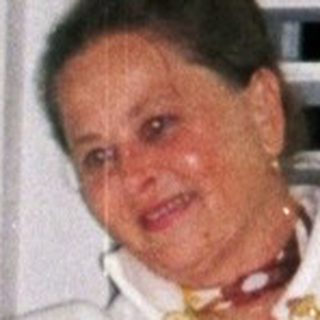 Woman in a robe stands near a window, smiling.