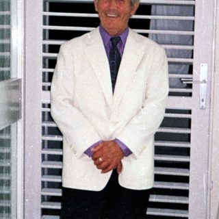 Man stands in a room with a shuttered door.