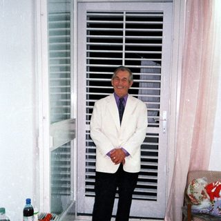 Man stands in a room with a shuttered door.