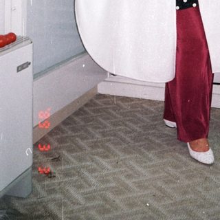 Woman in a white robe stands near a window.