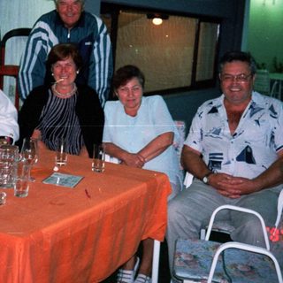 Group of people seated around a table outdoors at night.