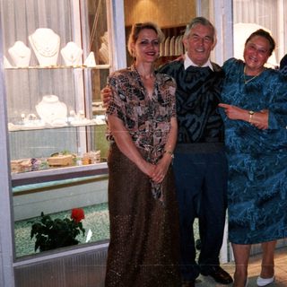 Four people posing outside a store with jewelry displays.