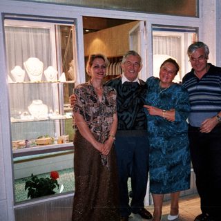 Four people posing outside a store with jewelry displays.