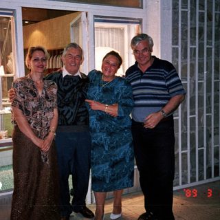 Four people posing outside a store with jewelry displays.