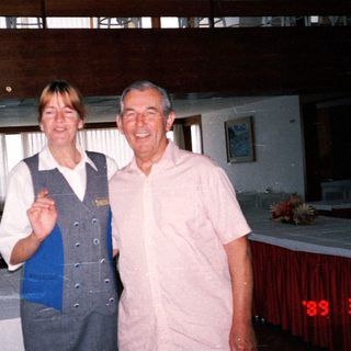 A woman in uniform and man posing in a dining room.