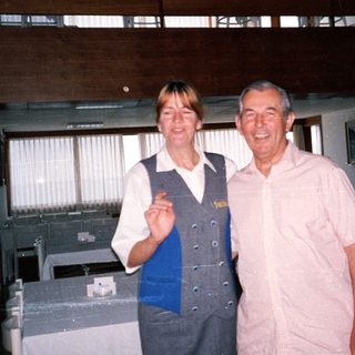 A woman in uniform and man posing in a dining room.