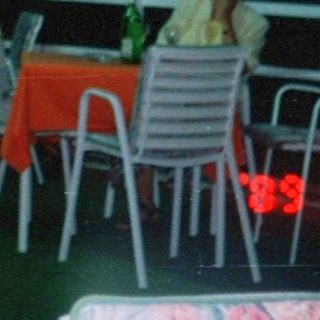 Couple dancing outdoors at night under a shelter.