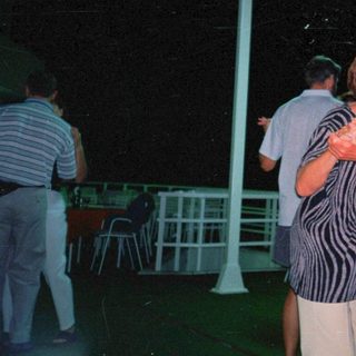 Couple dancing outdoors at night under a shelter.