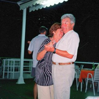 Couple dancing outdoors at night under a shelter.