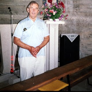 Man stands in a room with religious statues and artwork.