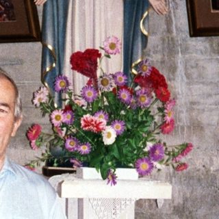 Man stands in a room with religious statues and artwork.