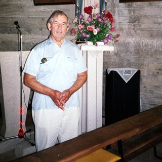 Man stands in a room with religious statues and artwork.