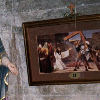 Man stands in a room with religious statues and artwork.