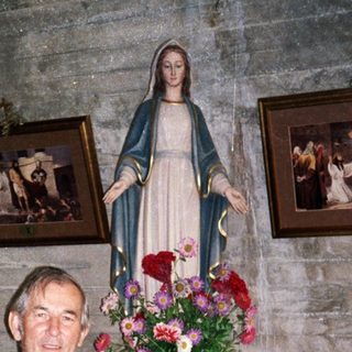 Man stands in a room with religious statues and artwork.