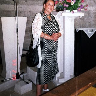 Woman stands in a church with statue and artwork.