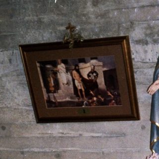 Woman stands in a church with statue and artwork.