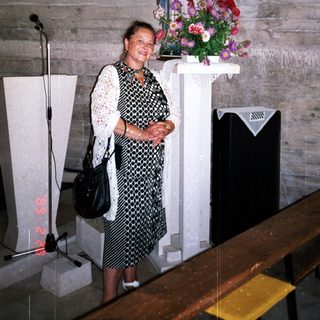 Woman stands in a church with statue and artwork.