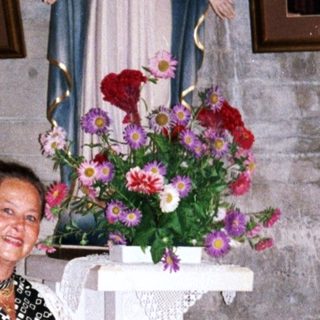 Woman stands in a church with statue and artwork.