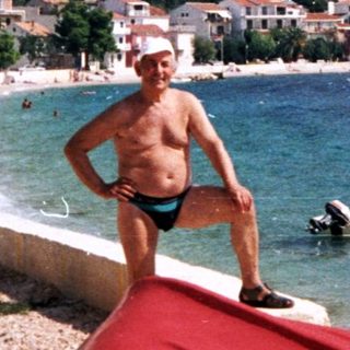 Man stands on a boat at a coastal town beach.