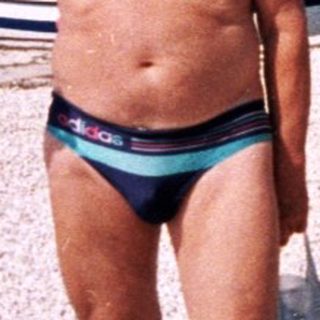 Man on a pebbled beach, holding an object, seaside.