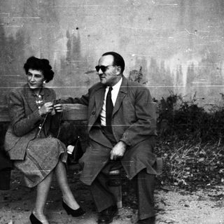 Couple seated on a bench in a monochrome setting.