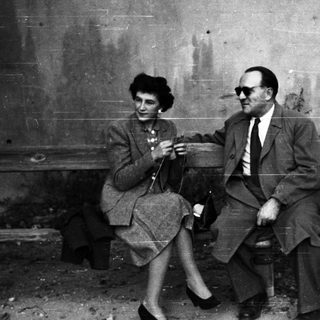 Couple seated on a bench in a monochrome setting.