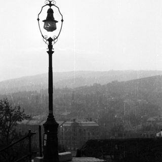 Vintage lamppost overlooks a town with visible rain.