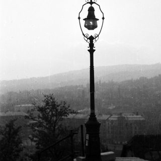 An antique lamp post stands overlooking a hazy landscape.