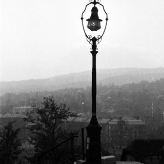 Ornate lamppost overlooks a town on a foggy day.