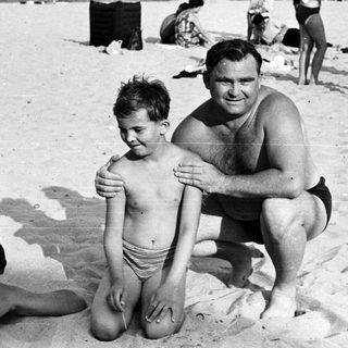 Black and white photo of people on a sandy beach.