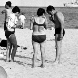 Black and white photo of people on a sandy beach.