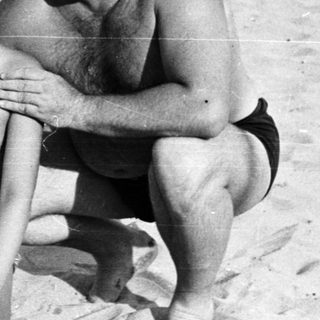 Black and white photo of people on a sandy beach.