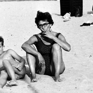 Black and white photo of people relaxing on a beach.