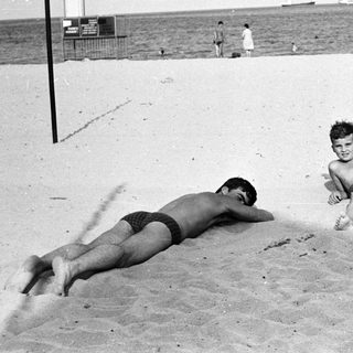 Black and white photo of people relaxing on a beach.