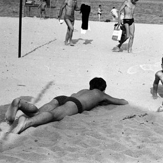 Black and white photo of people relaxing on a beach.