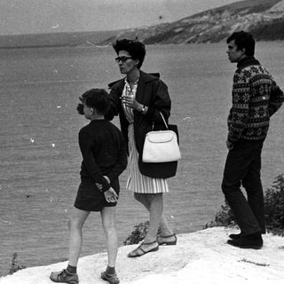 Family stands overlooking the sea from a clifftop.