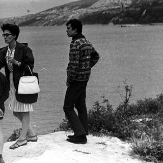 Family stands overlooking the sea from a clifftop.