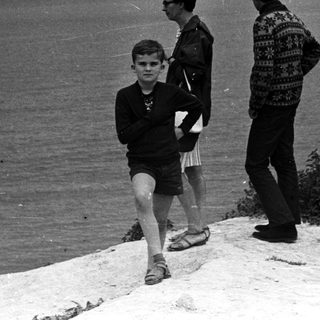 Black and white photo of three people by the sea.