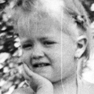 Black and white photo of a toddler standing outdoors.