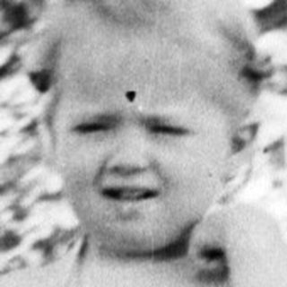 Black and white photo of a child standing outdoors.