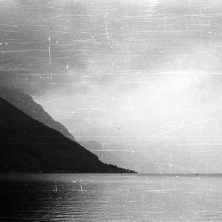 Monochromatic landscape features a body of water and mountains.