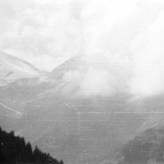 Mountain range obscured by clouds in a monochrome image.