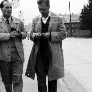 Two men in coats walk down a street.