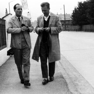 Two men in coats walk down a street.