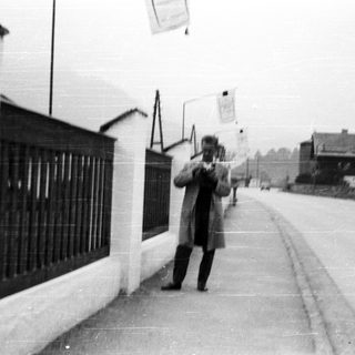 Man stands near a wall on a street.