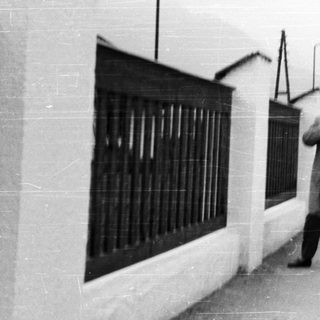 Man stands near a wall on a street.