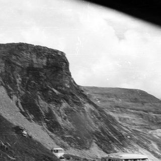 Monochromatic image depicts a large, steep, rocky mountain landscape.