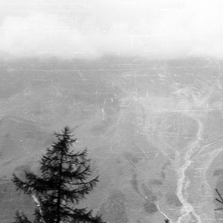 Here's a brief summary of the image: Overcast landscape with trees, a river, and distant town.