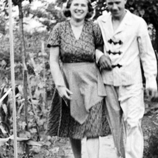 Couple walks along a path in a garden.