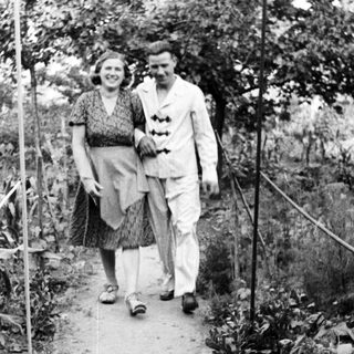 Couple walks along a path in a garden.